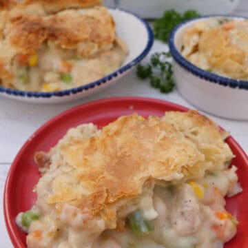 A white surface with three plates with a serving of chicken pot pie casserole on each, and a title overlay at the top.