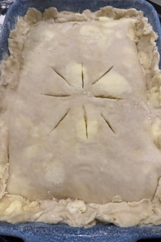 A 9x13 baking dish filled with a chicken pot pie casserole ready to be put in the oven.