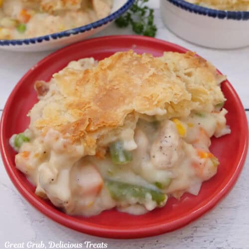 A red plate on a white surface with a serving of chicken pot pie casserole on it.