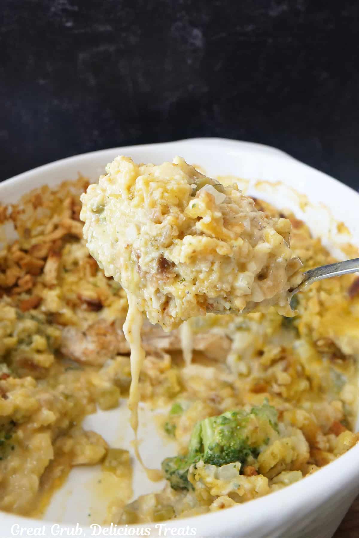 A white casserole dish with a big spoon scooping out some chicken casserole.
