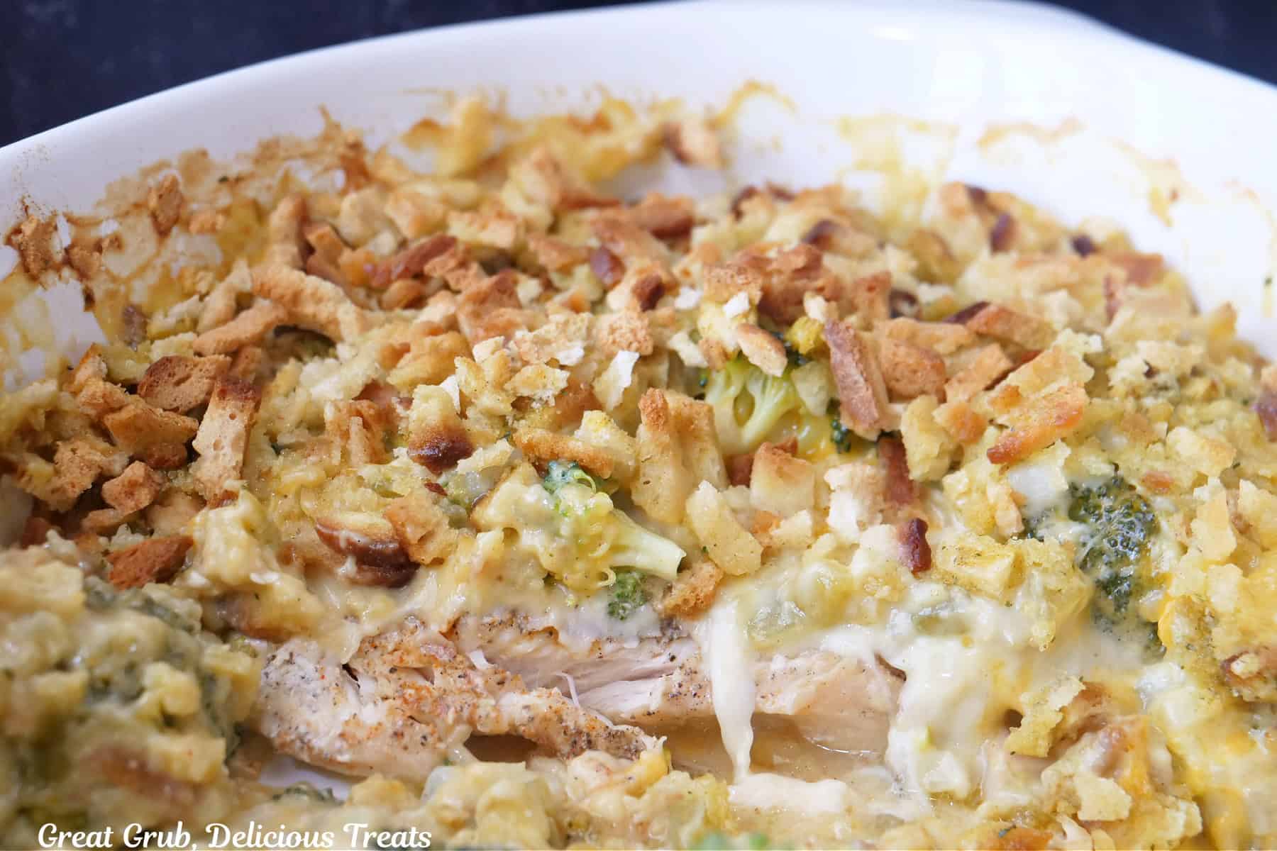 A white casserole dish with chicken swiss cheese stuffing casserole in it.