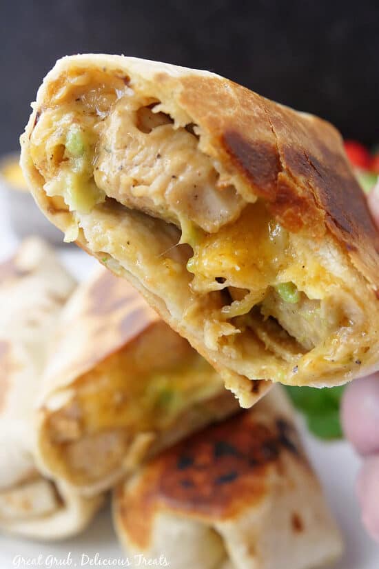 A close up of half a chipotle ranch grilled chicken burrito with a bite taken out of it.
