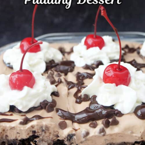 A chocolate layered dessert with brownies and chocolate pudding with whipped cream and cherries on top.