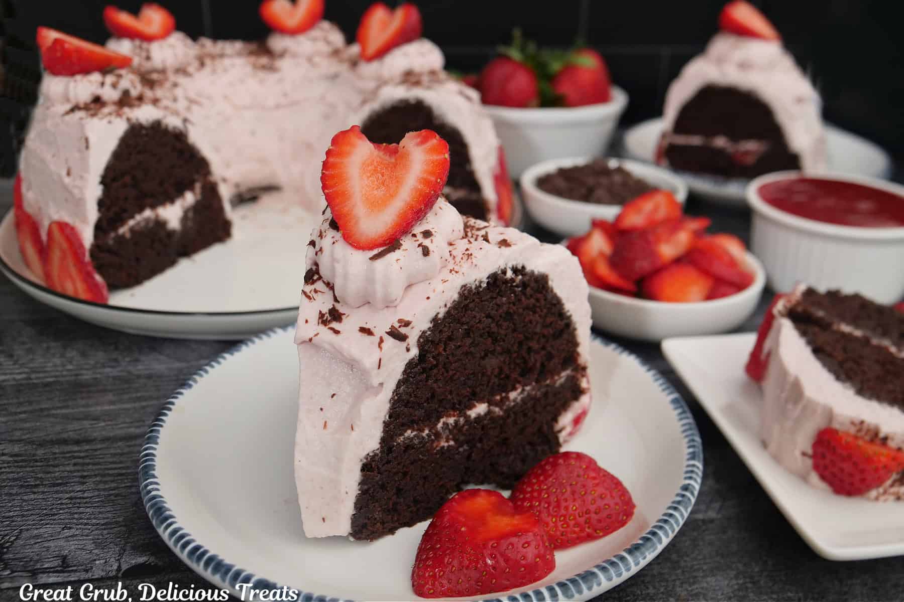 A round white plate with blue trim with a slice of chocolate bundt cake with strawberry whipped cream frosting.