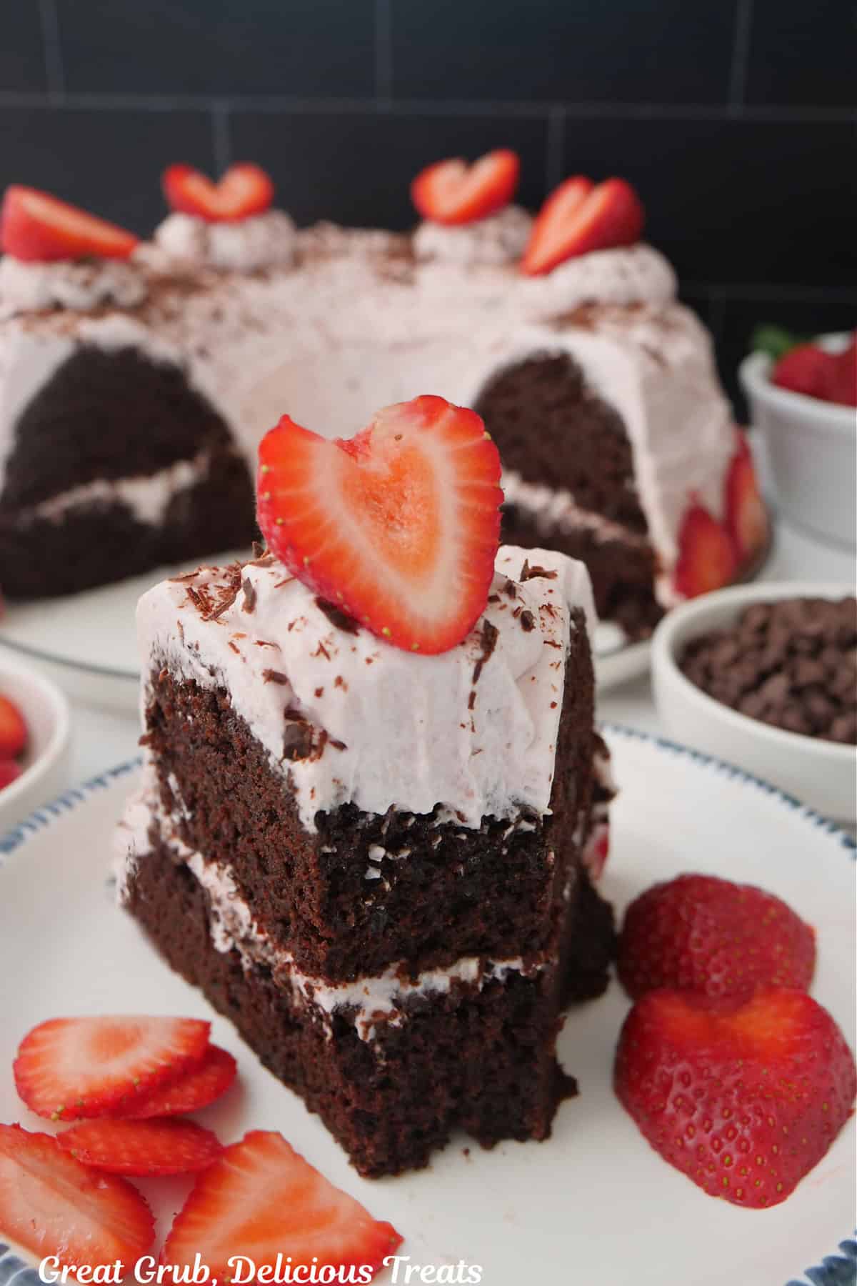 A slice of chocolate bundt cake with strawberry cream frosting with a bite taken out, and more cake in the background.