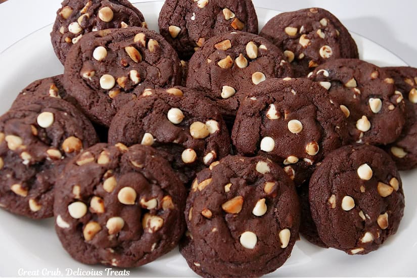 A white large round plate with over a dozen cookies on it.