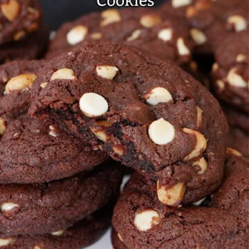 A few stacks of chocolate white chocolate macadamia nut cookies with a bite taken out of one of them.