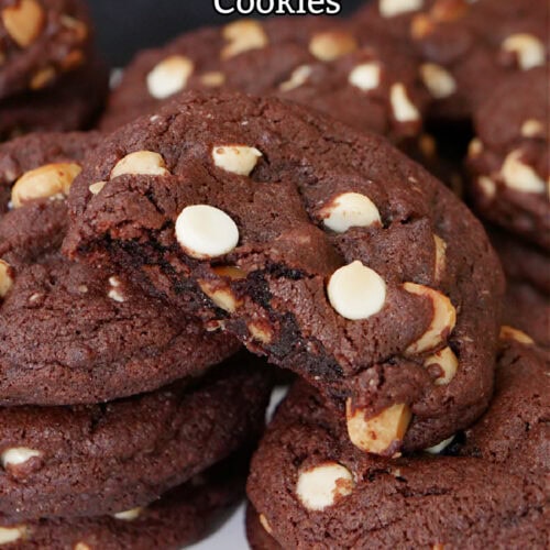 A few stacks of chocolate white chocolate macadamia nut cookies with a bite taken out of one of them.