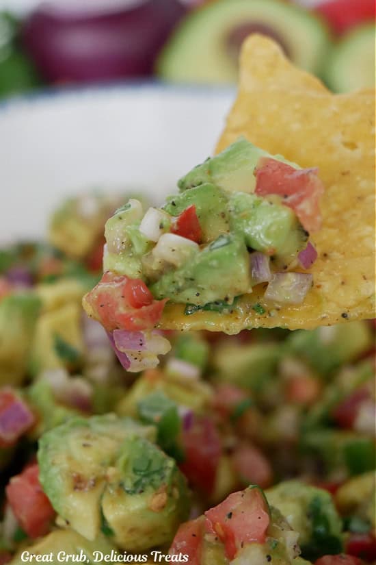A corn tortilla chip with chunky avocado salsa on it.