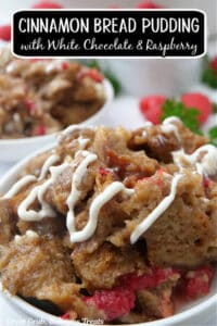 A close up of a white bowl filled with a serving of cinnamon bread pudding with white chocolate drizzled over the top.