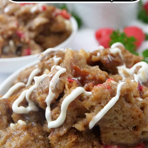 A close up of a white bowl filled with a serving of cinnamon bread pudding with white chocolate drizzled over the top.