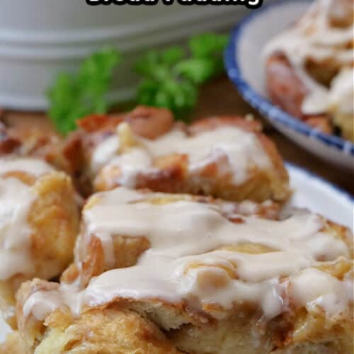 A serving of cinnamon raisin bread pudding on a white plate with blue trim.