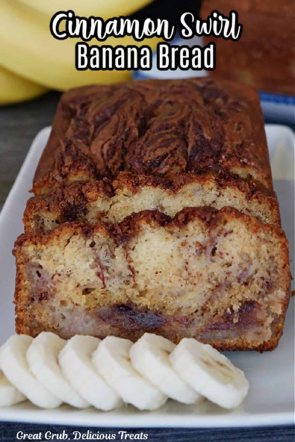 A rectangle white plate with a loaf of banana bread on it that has been sliced with sliced bananas on the plate.