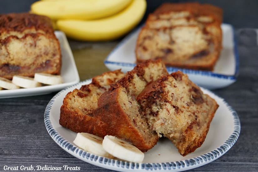 White plates with blue trim with slices of banana bread on them.