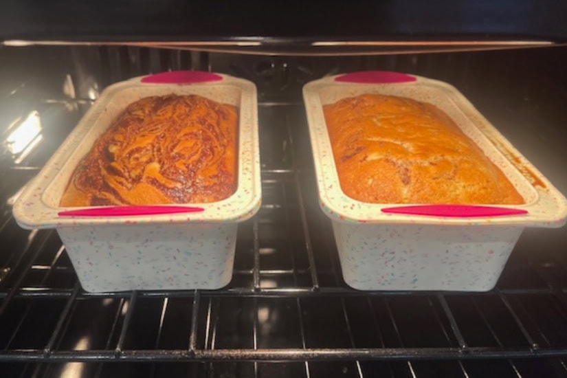 Two loaf pans in the oven baking the banana bread.