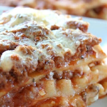 A slice of lasagna on a white plate.