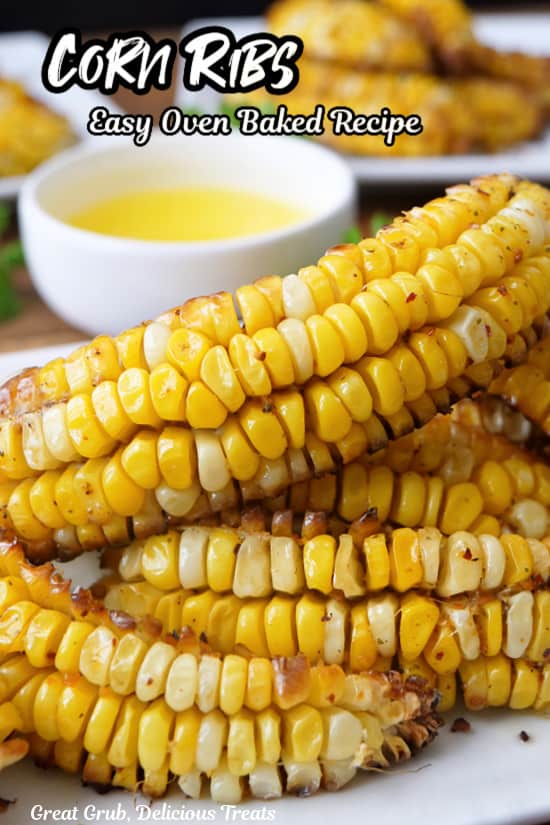 A white plate with a stack of corn ribs on it with a small white bowl filled with melted butter in the background.