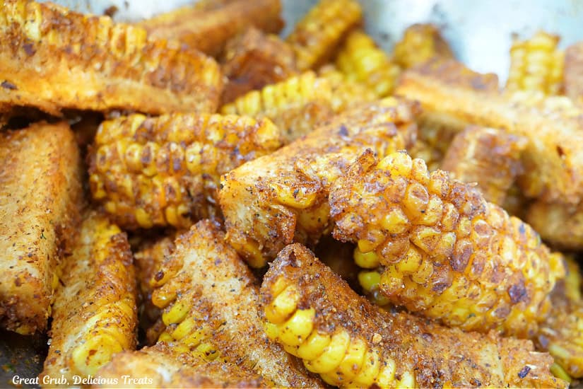 A bunch of seasoned corn ribs in a bowl showing all the zesty seasonings on them.