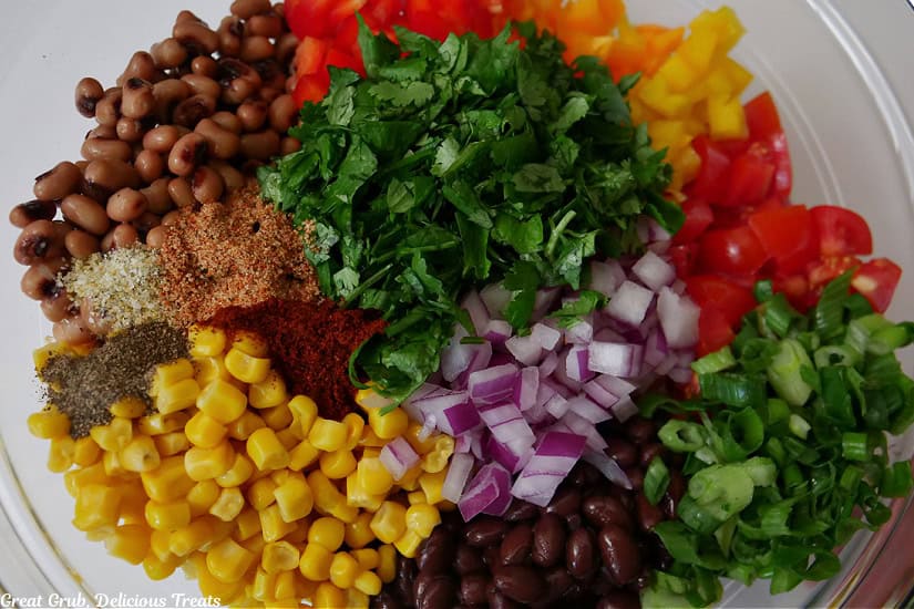 A clear glass bowl filled with all the ingredients for cowboy caviar.