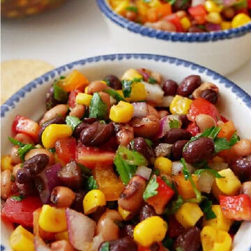 Two white bowls with blue trim and a clear glass bowl filled with cowboy caviar.