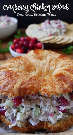 A round crescent filled with cranberry chicken salad with a plate of crackers and a small white bowl filled with fresh cranberries.