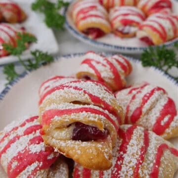 A white surface with cranberry pastry bites on a white plate with blue trim.