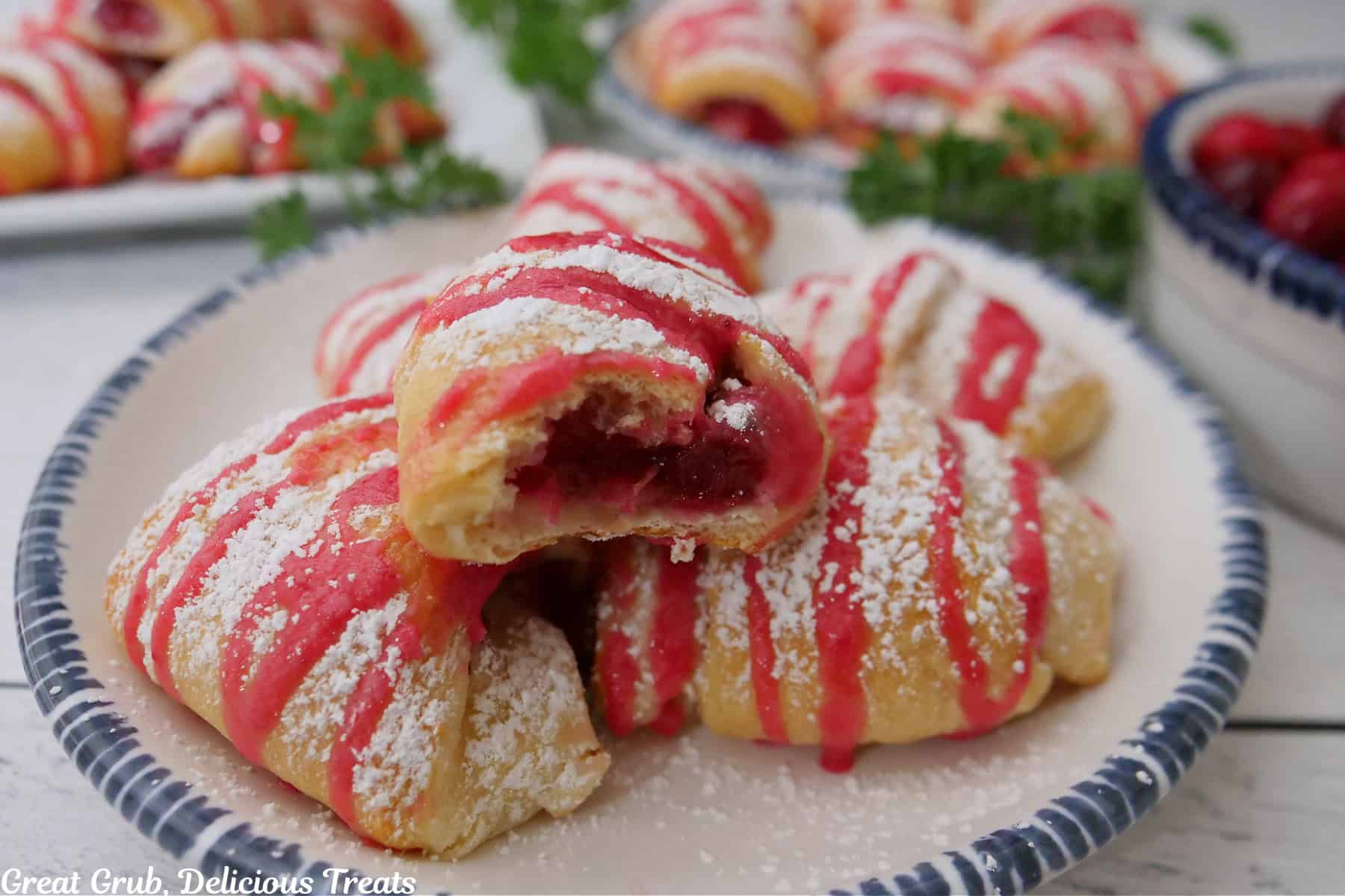 A white round plate with blue trim with five mini cranberry pastry bites on it.