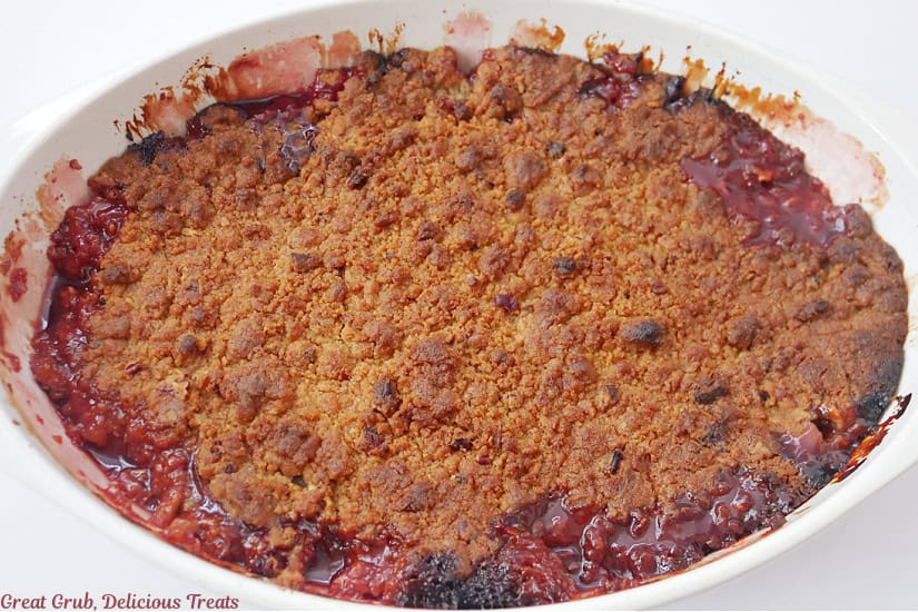 A white oval baking dish with cranberry crisp right after removing from the oven.