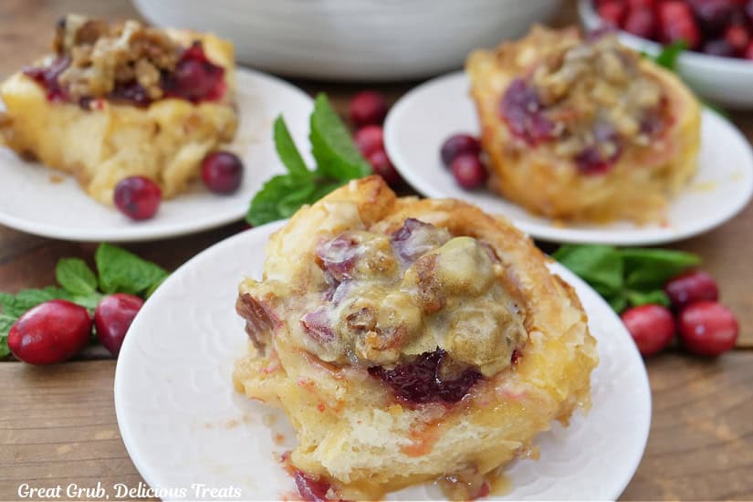Three round plates on a wood surface with cinnamon rolls on each plate.