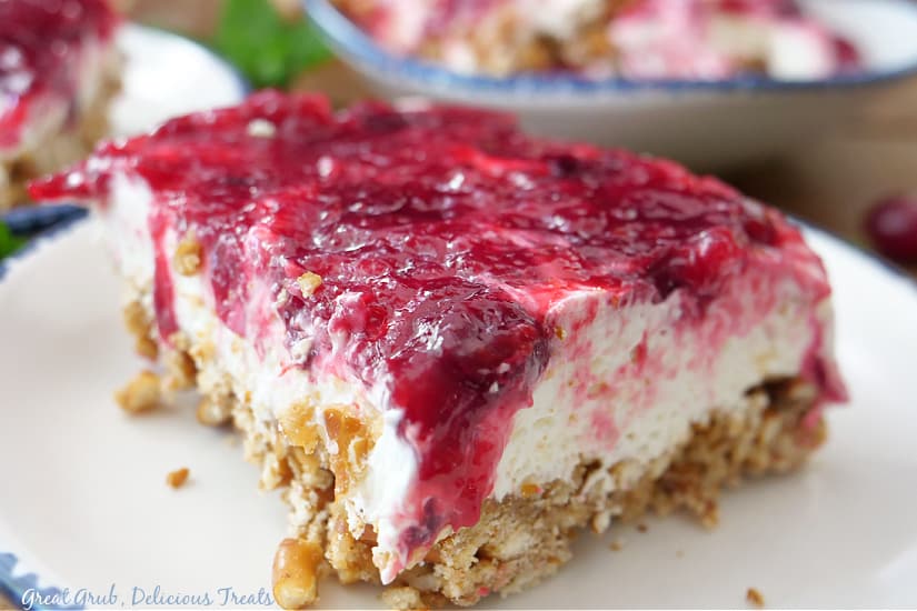 A serving of pretzel salad with cranberries on a white plate with blue trim.