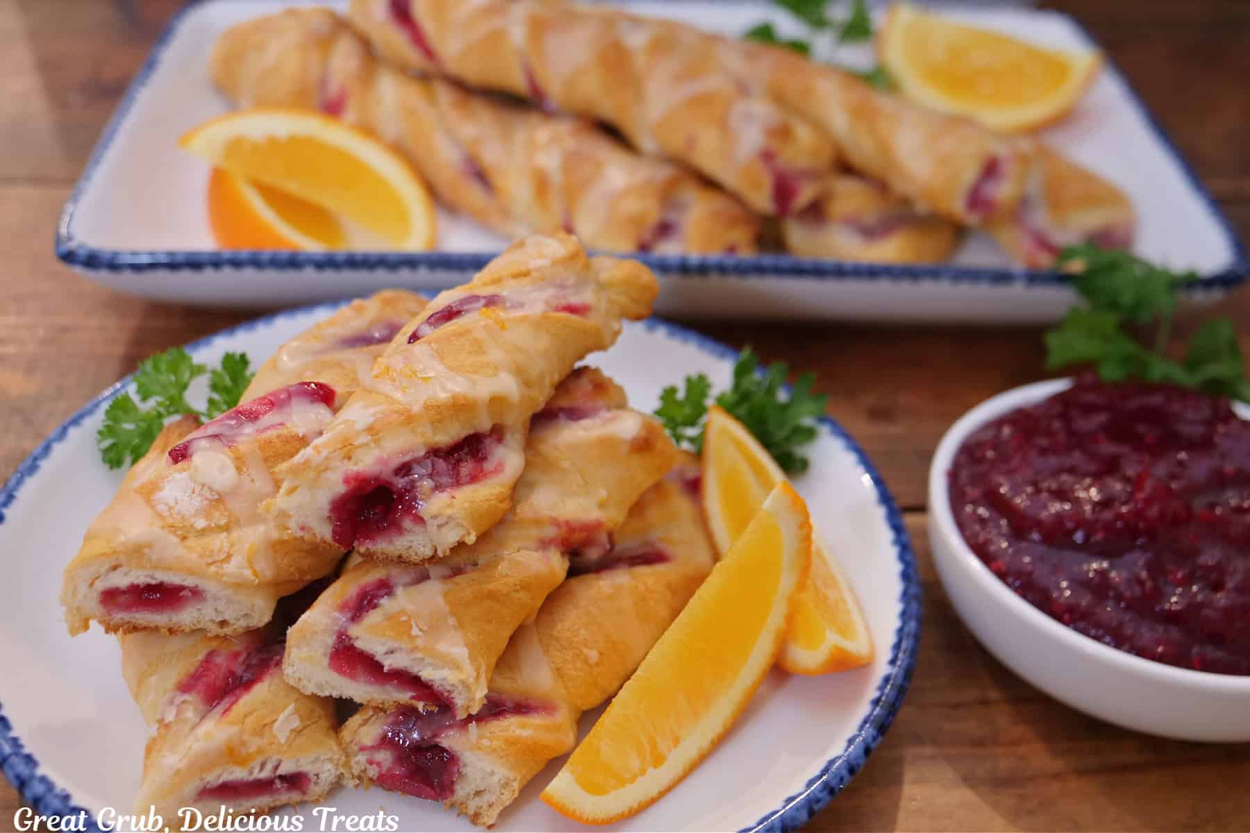 A round white plate with blue trim with a stack of cranberry twists on it with more in the background.