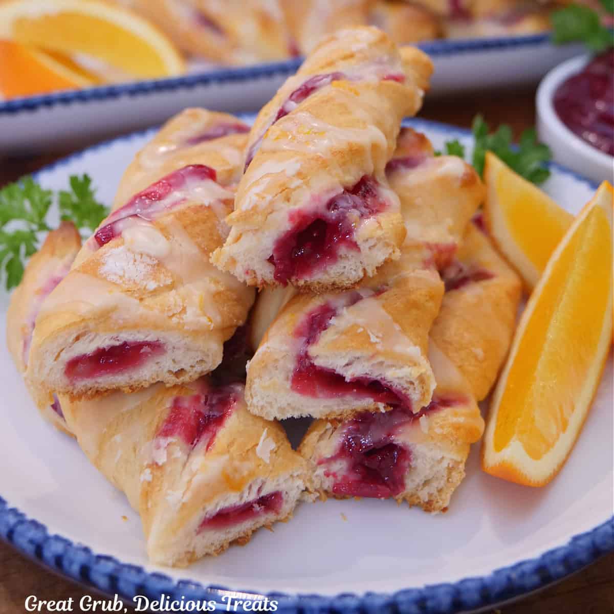 A white round plate with blue trim with a small stack of cranberry twists with orange glaze on it.