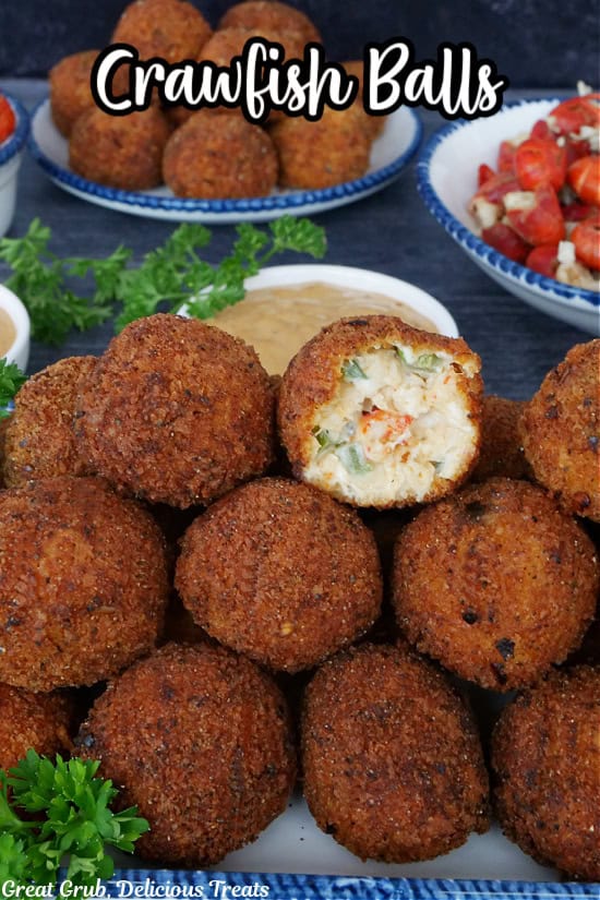 A stack of deep fried crawfish balls on a white plate with a bite taken out of the ball on top.