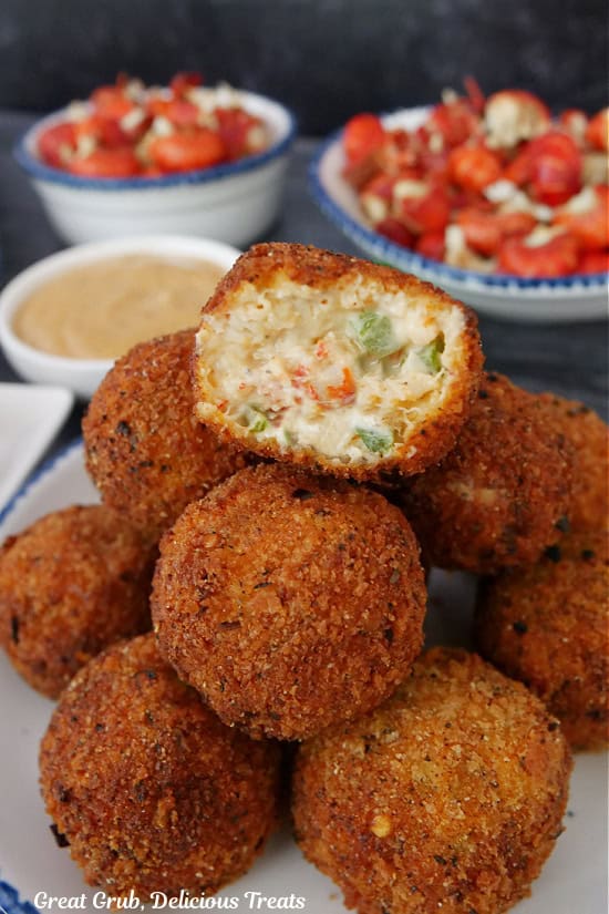 A stack of 8 crawfish balls on a white plate with blue trim with a bite taken out of the one on top.