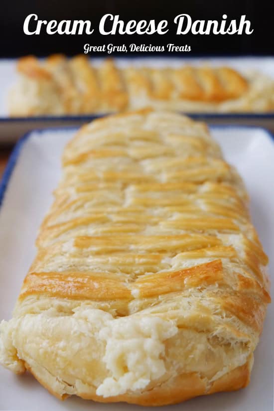 A close up of a cheese danish braid on a white plate with blue trim.