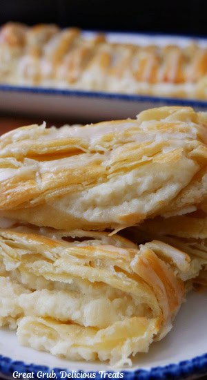 A close up of a few slices of cheese danish on a white plate with blue trim.
