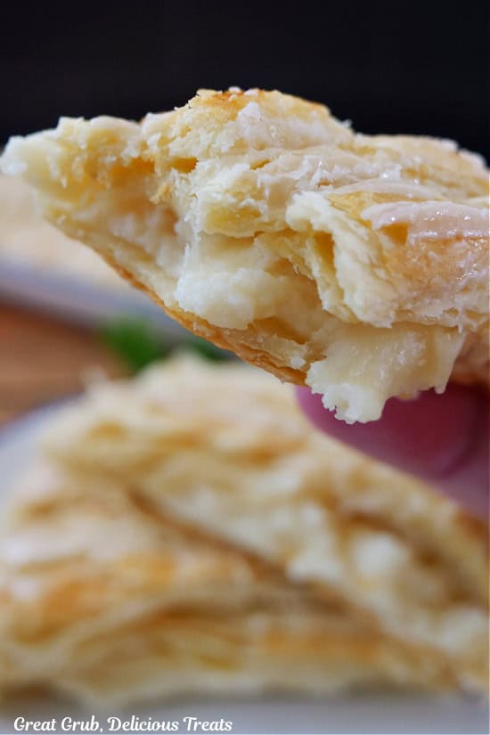 A close up of a slice of cheese danish with a few bites taken out of it.
