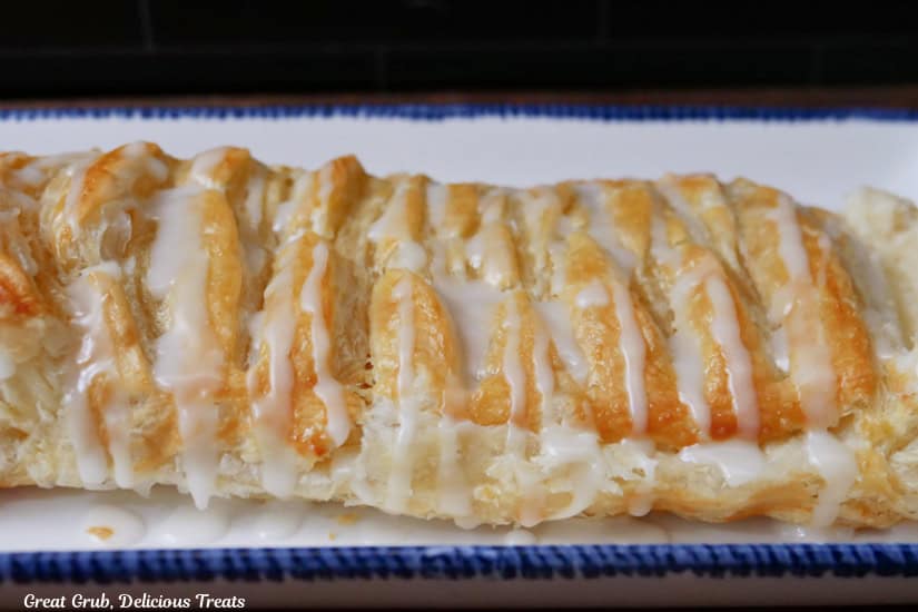 A blue trimmed white oblong plate with a cheese pastry braid on it.