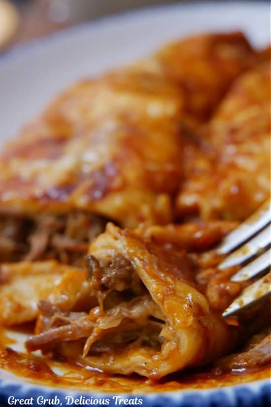 A bite of beef enchilada on a fork.