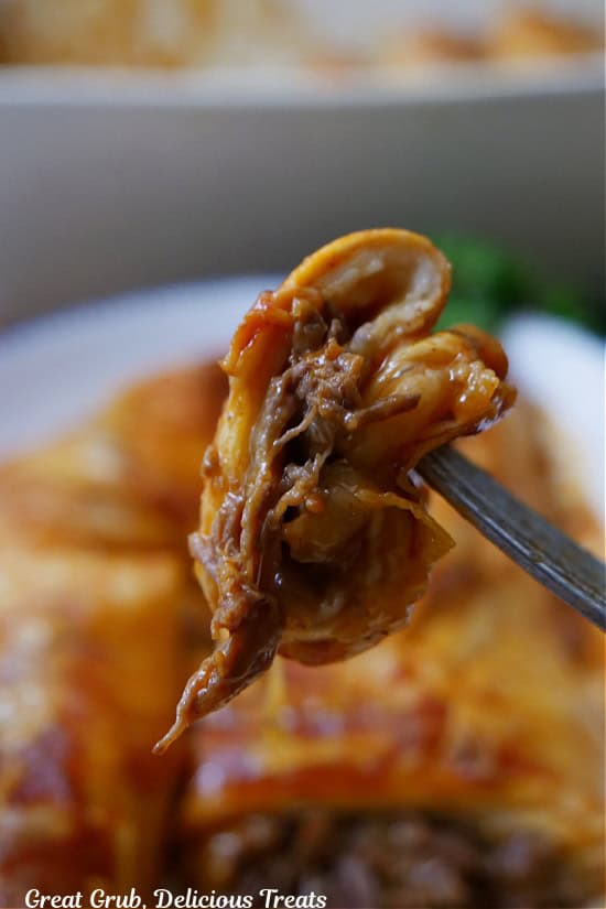 A bite of beef enchilada on a fork.
