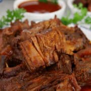 Boneless beef ribs on a white plate with blue trim, and the title of the recipe at the top.