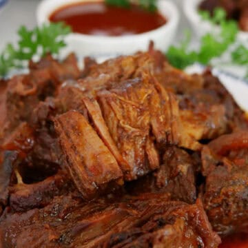 Boneless beef ribs on a white plate with blue trim, and the title of the recipe at the top.