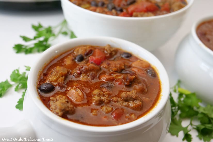 A horizontal photo of white bowls filled with homemade chili.