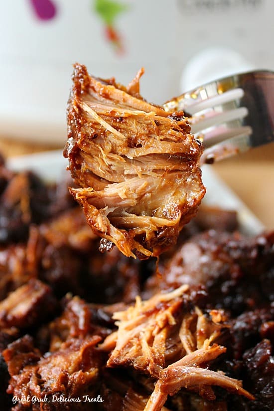 These Crock Pot Country-Style Pork Ribs are fork tender, cooked in barbecue sauce and coke, and are delish! A close up of a bite of pork ribs on a fork.