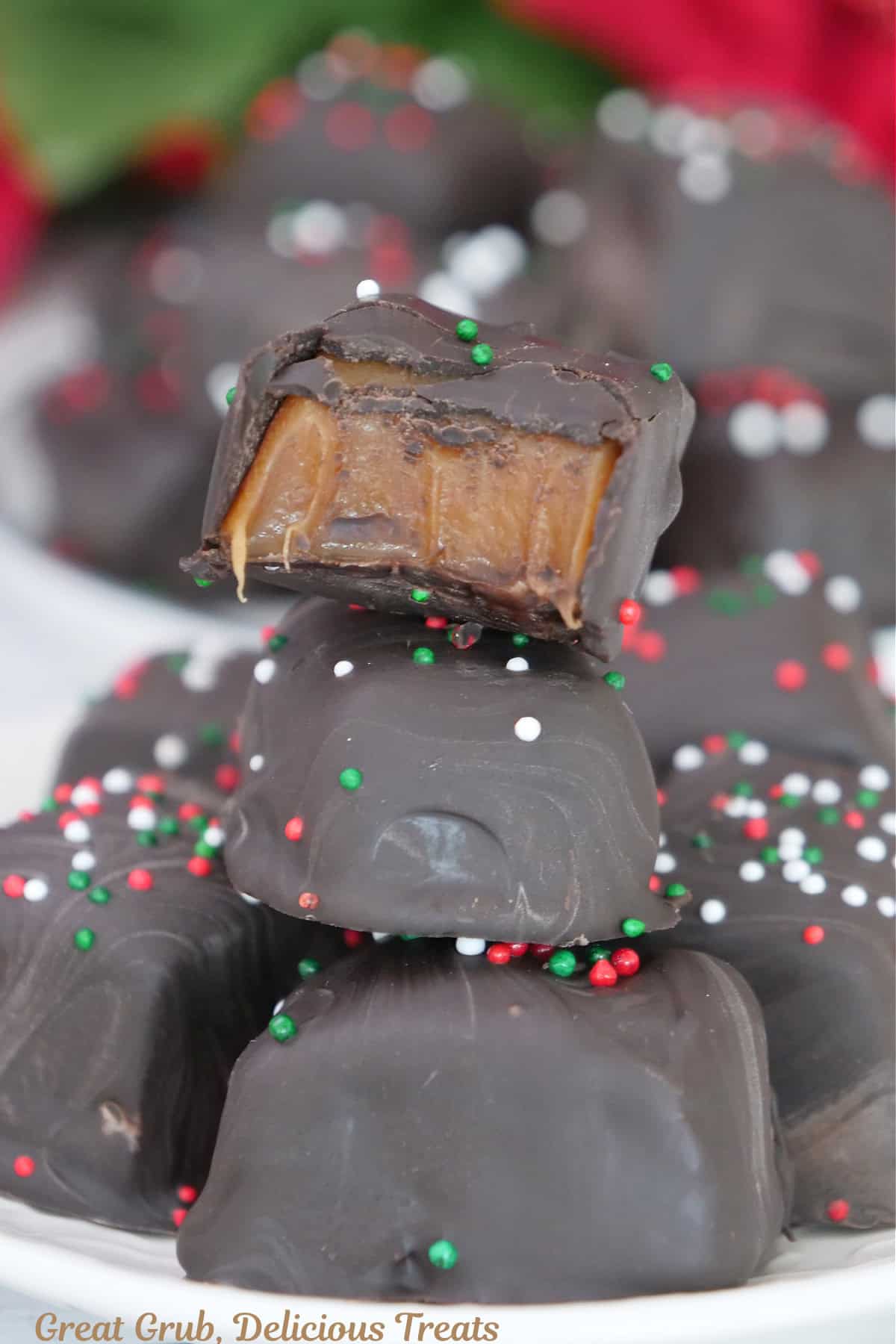 A small stack of dark chocolate caramel on a white plate with a bite taken out of the caramel on top.