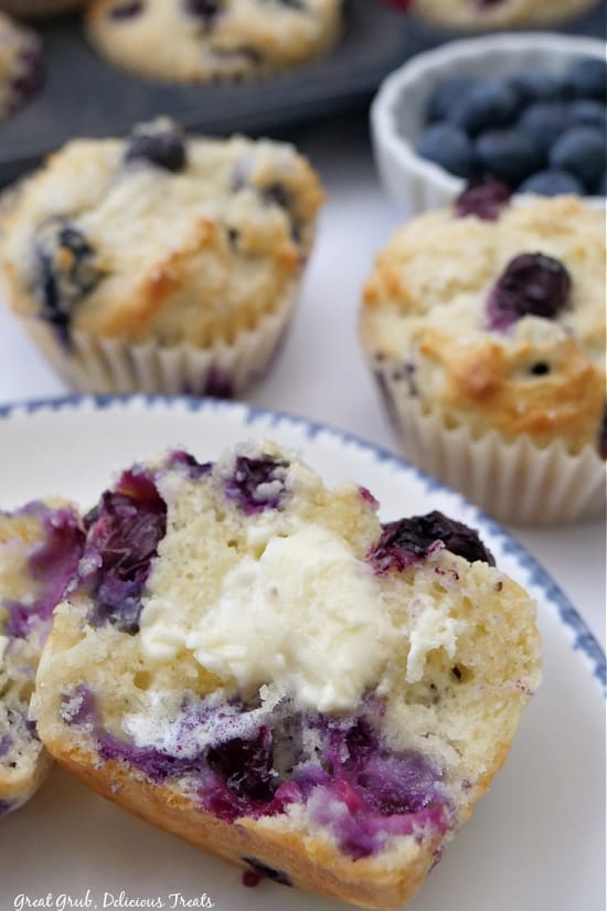 A plate with a muffin cut in half on it with some butter on top.