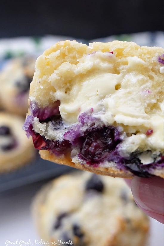 A half of a muffin being held up with some melted butter on it.