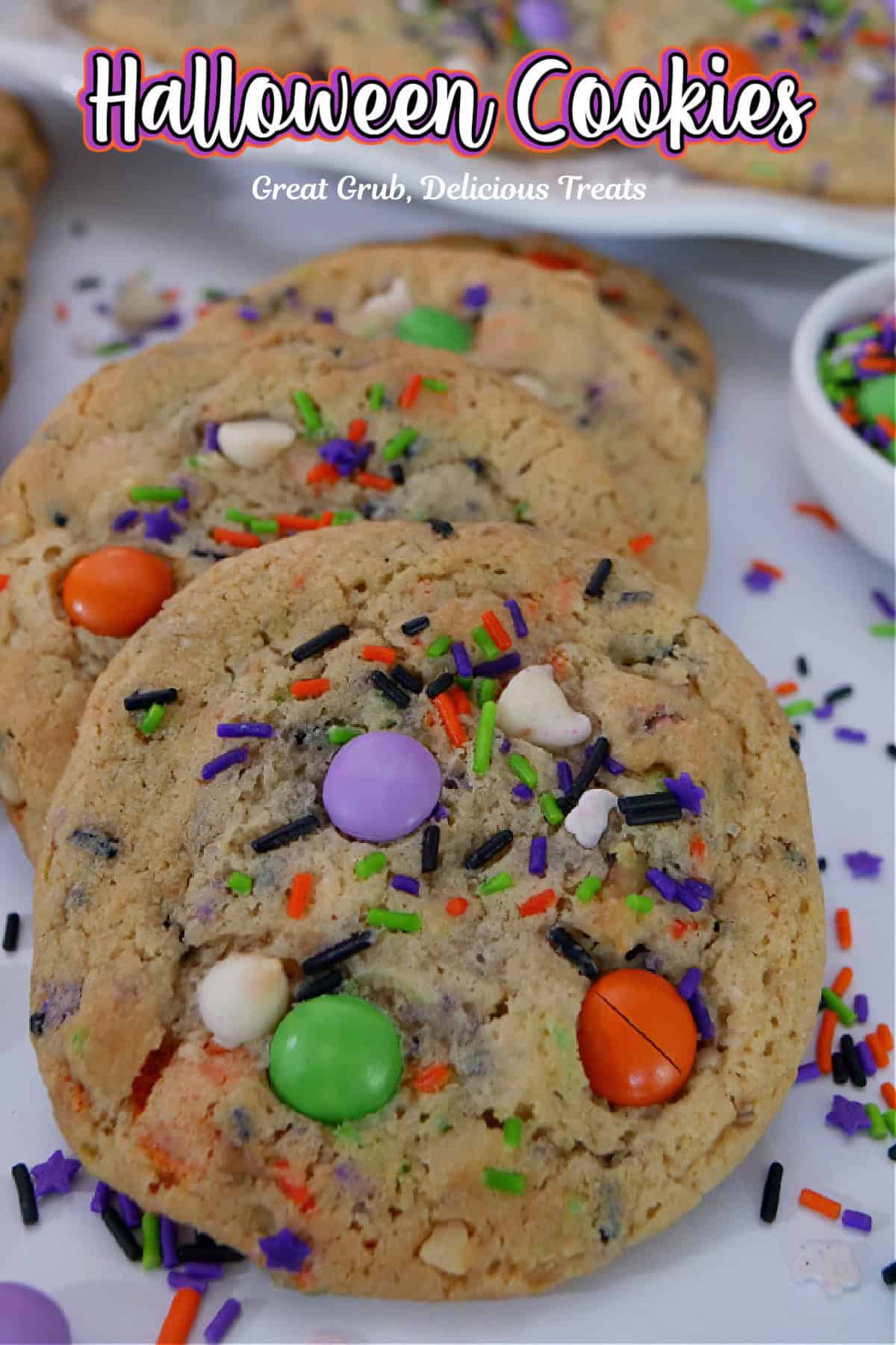 A few Halloween cookies on a white surface with candy sprinkles placed around the cookies.