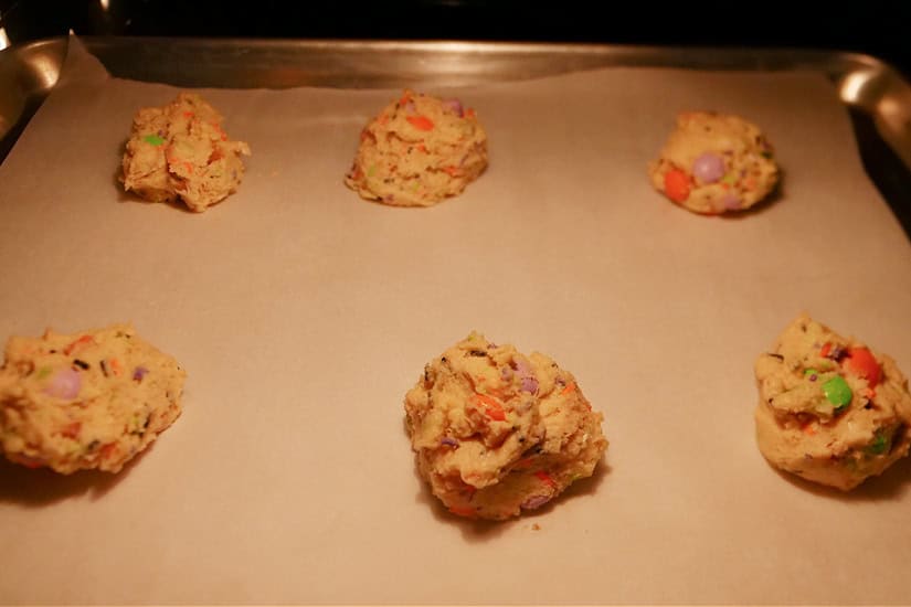 A baking sheet in the oven with six cookies on it.