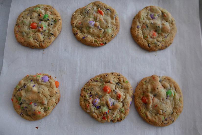 A baking sheet with six baked cookies on parchment paper.